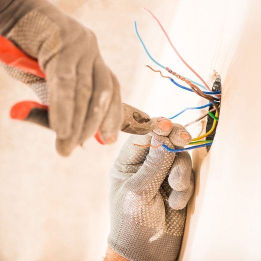 an electrician is working on wires in the wall with his gloved hand holding them