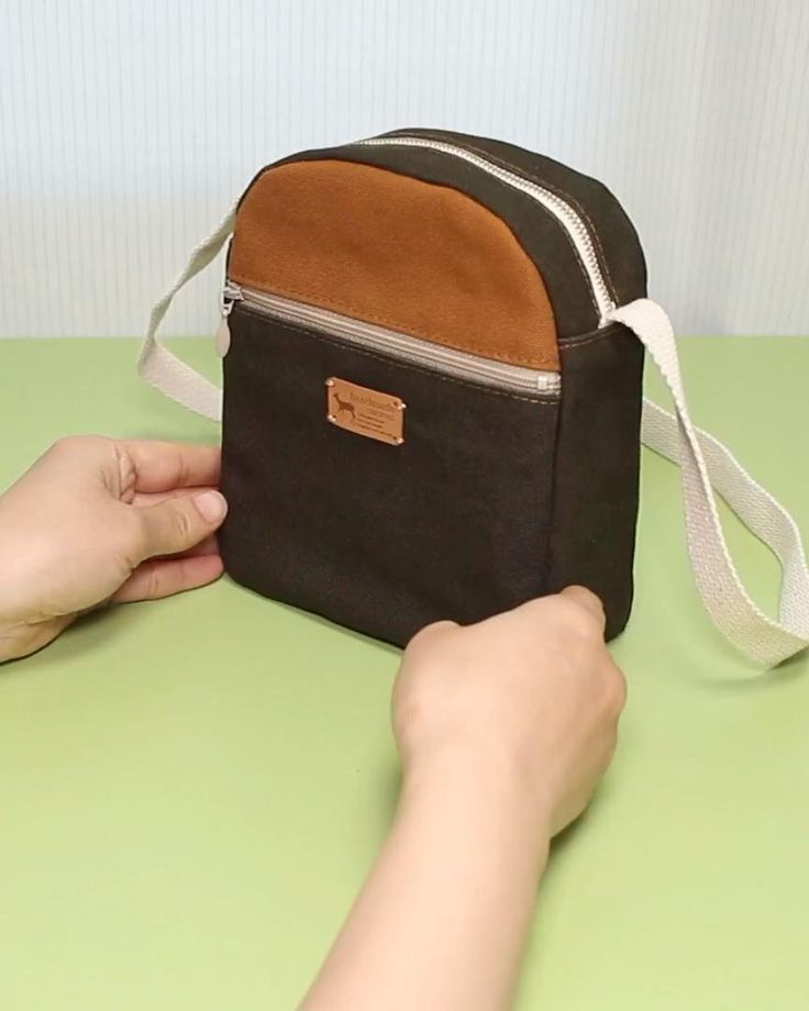 a person holding onto a black and brown bag on a green table with white straps