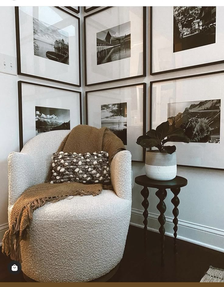 a white chair sitting in front of a wall with pictures on it's walls