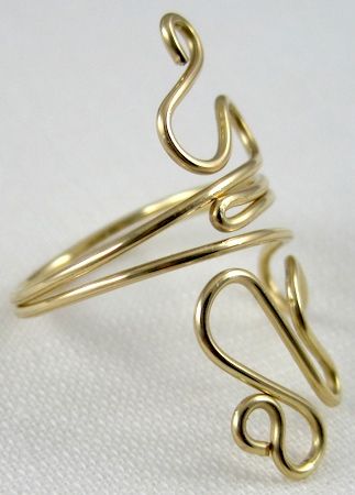 a gold ring with two spirals on the front and back sides, sitting on a white surface