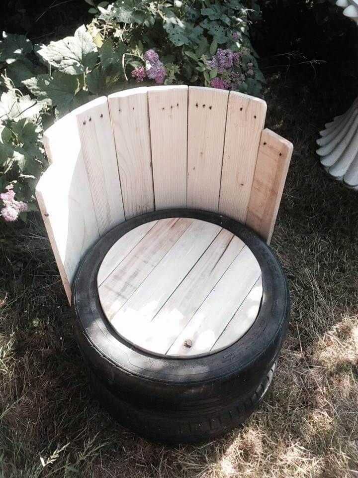 a wooden bench made out of an old tire is sitting in the grass next to some flowers