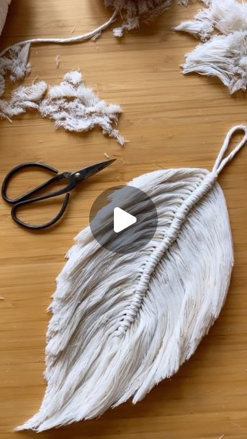 a pair of scissors sitting on top of a wooden table next to some white feathers