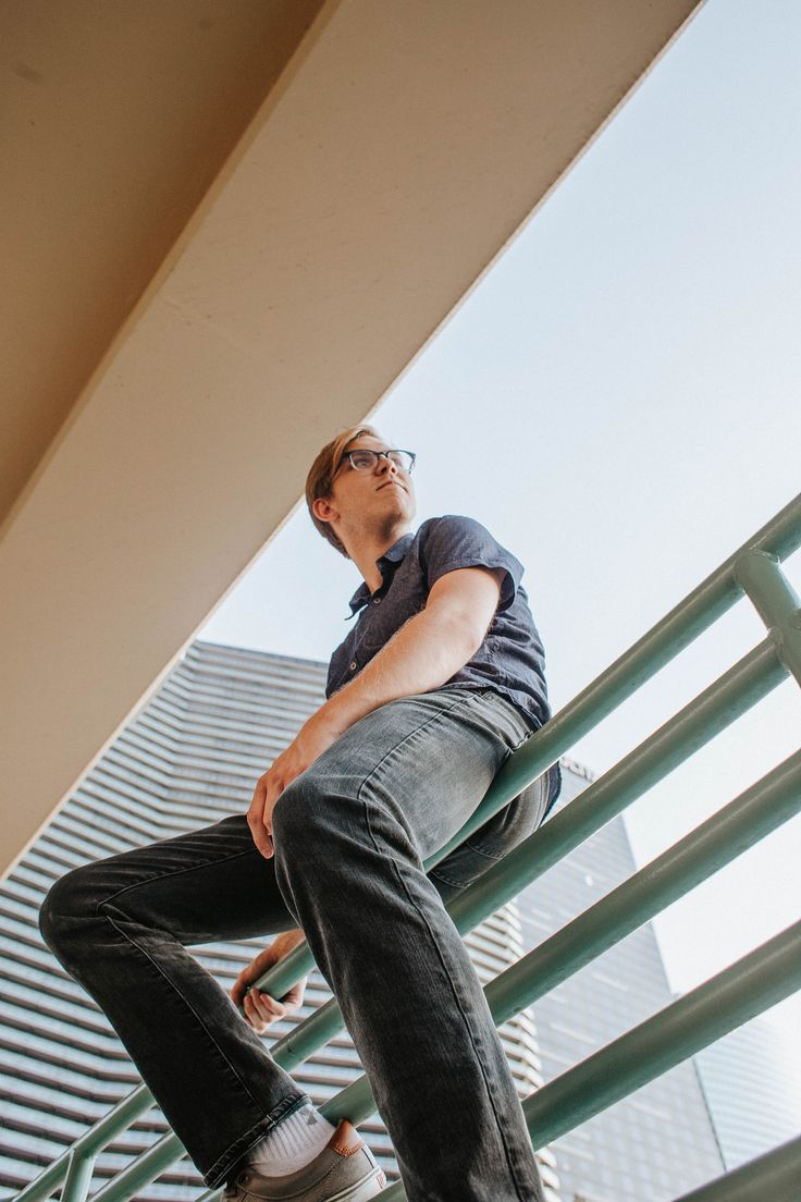 a man sitting on top of a metal hand rail