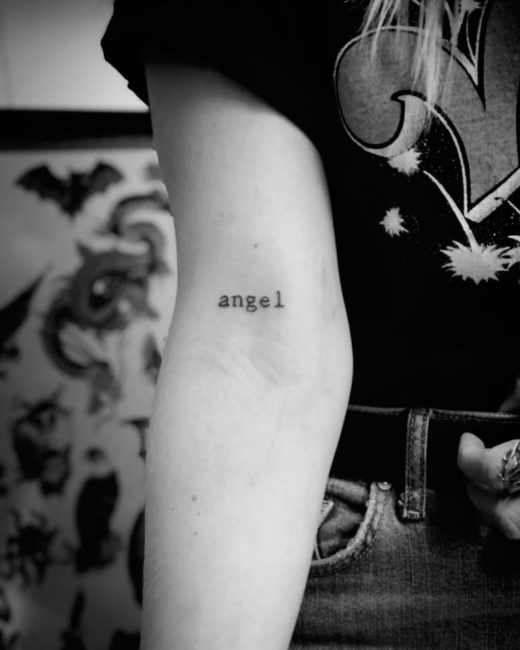 a woman with a small tattoo on her arm that says'angel'in black and white