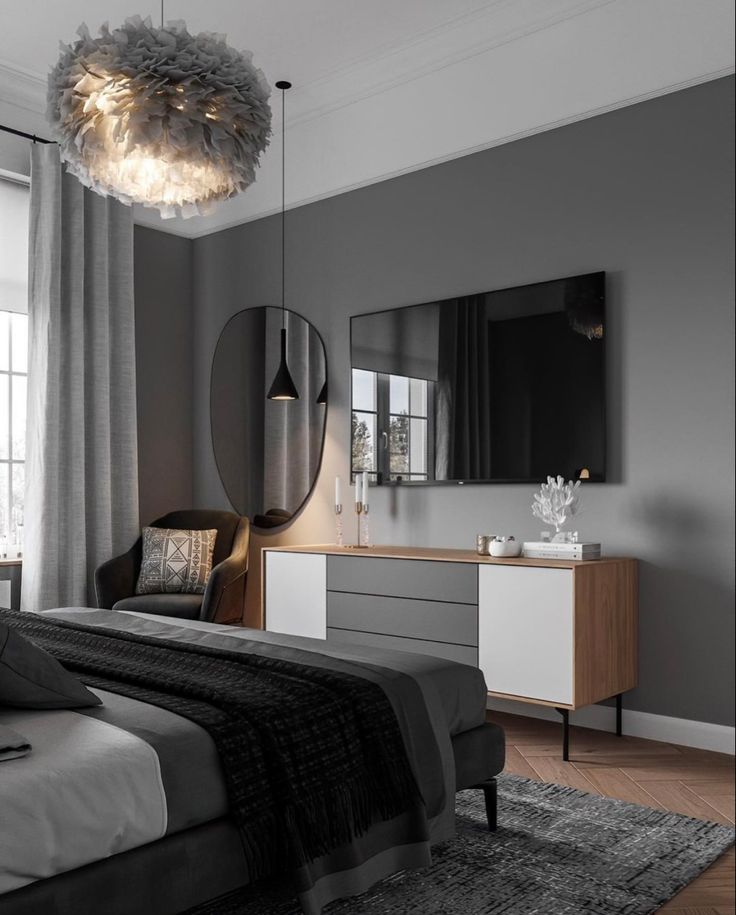 a bedroom with gray walls and furniture in the corner, along with a large mirror on the wall