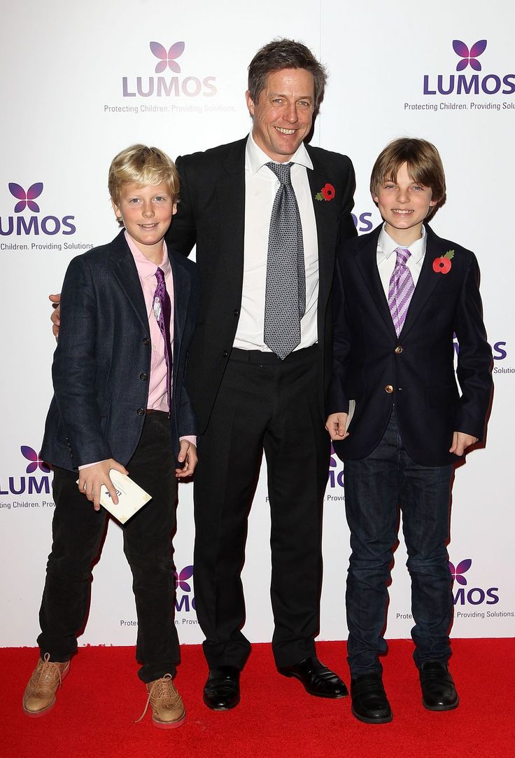 two boys and an older man standing on a red carpet at the lumos awards