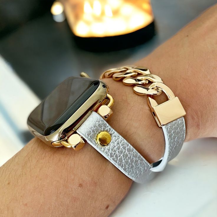 an apple watch on someone's arm with a gold chain around it and a silver bracelet