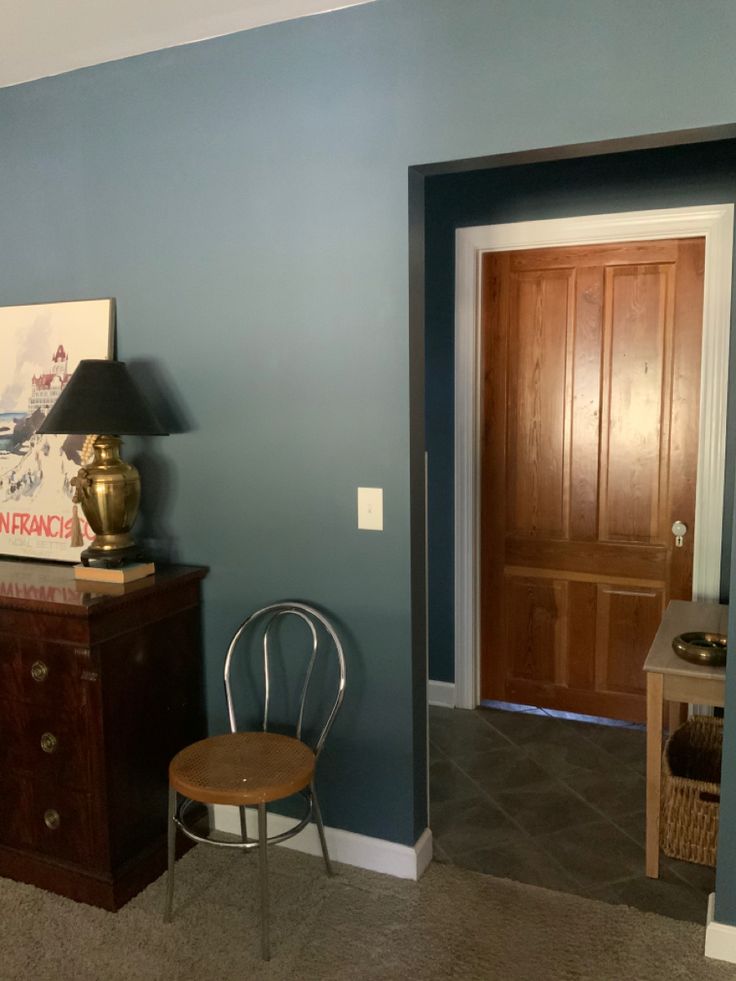 a room with blue walls and a wooden chair next to a lamp on a table