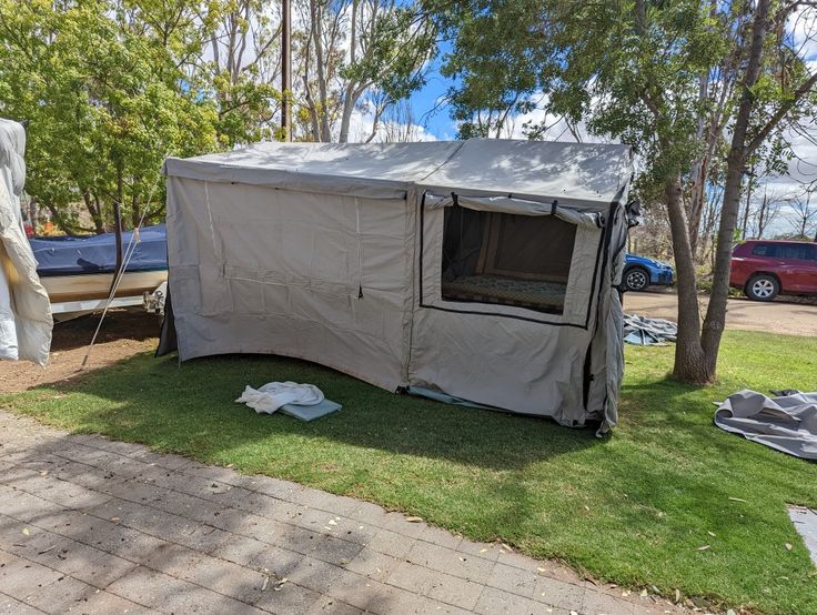 a tent is set up in the grass near some trees and other items on the ground