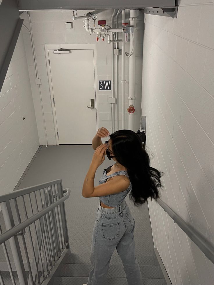 a woman is walking down the stairs with her hair blowing in the wind while wearing overalls