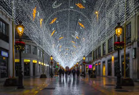 people are walking down the street covered in christmas lights