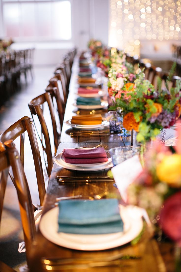 a long table set with place settings and flowers