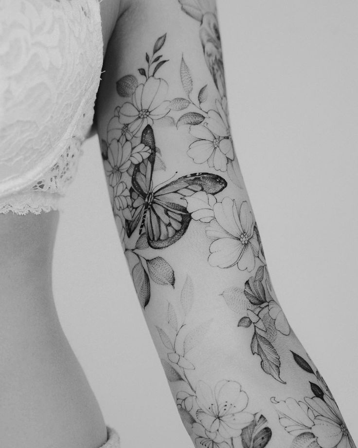 a woman's arm with flowers and butterflies tattooed on the side of her body