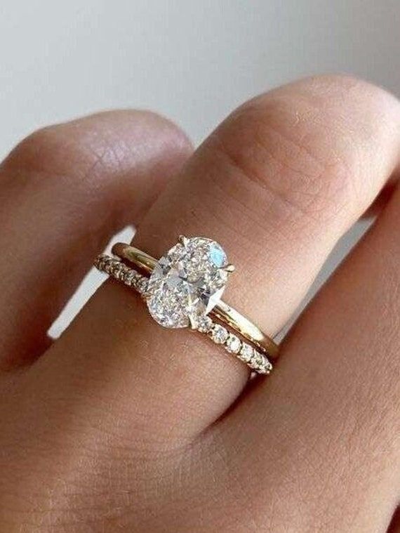 a woman's hand with a diamond ring on top of her finger and an engagement band