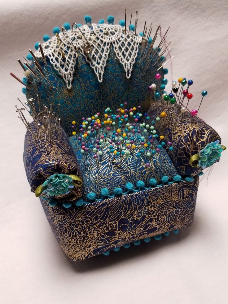 a blue chair with lots of pins and needles on the back, sitting in front of a white background