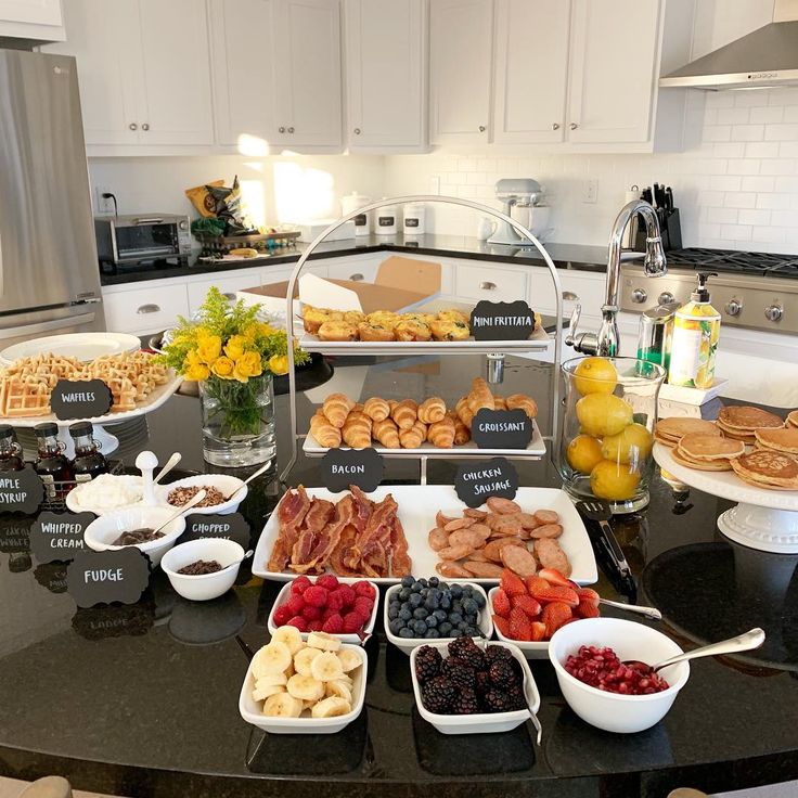 a table filled with lots of food on top of a black counter topped with plates and bowls