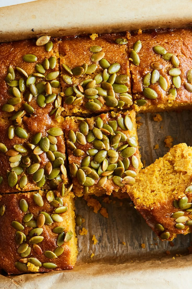 there is a cake that has been cut into squares and topped with pumpkin seed toppings