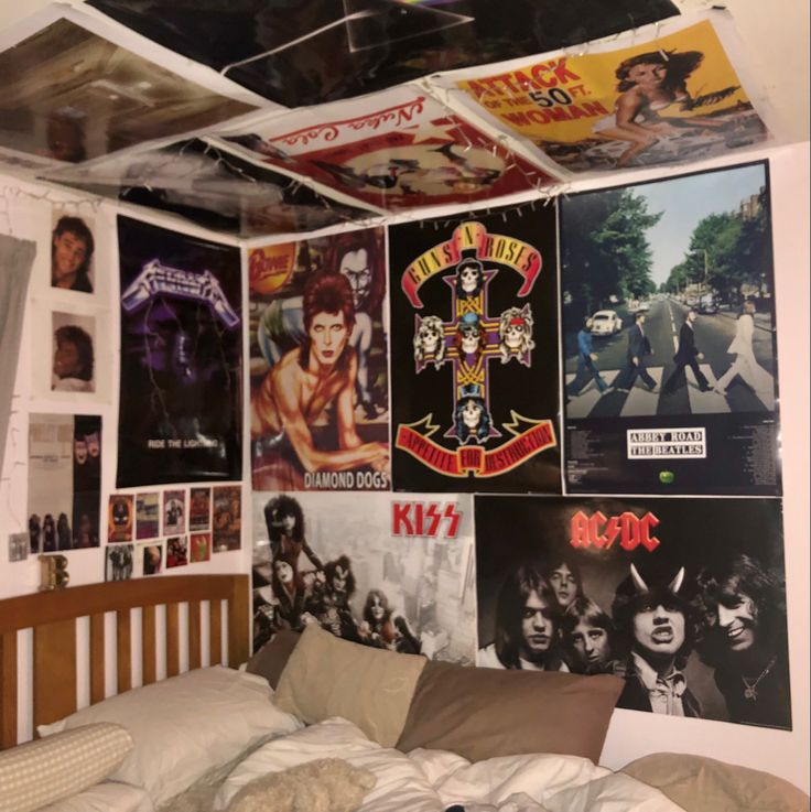 a bedroom with posters on the wall and a bed in front of it that is made up