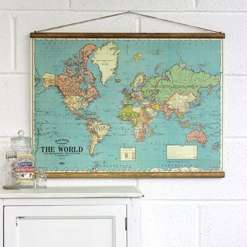 an old world map hangs on the wall above a white cabinet with a glass bottle