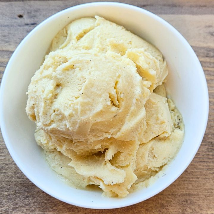 a white bowl filled with ice cream on top of a wooden table