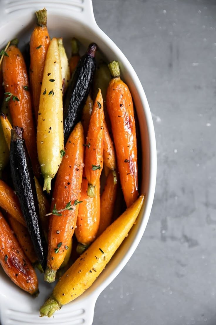 carrots and zucchini in a white bowl on top of a gray table