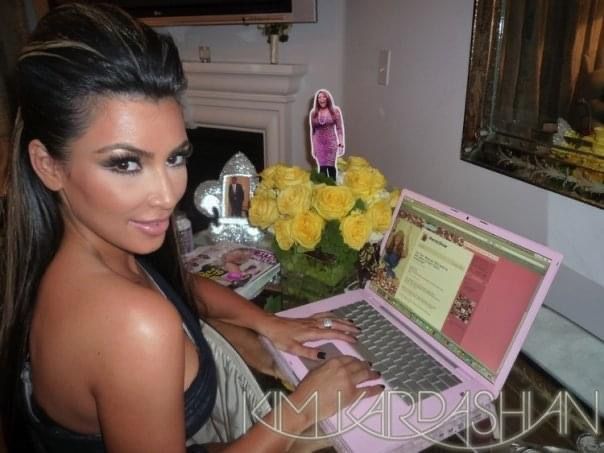 a woman sitting at a table with a laptop computer in front of her and yellow roses