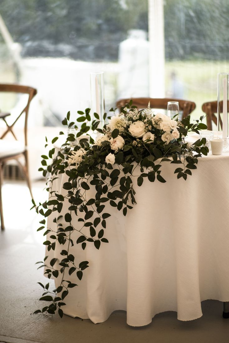 a table with white flowers and greenery on it is set up for a formal function