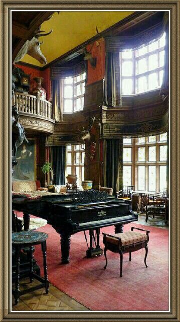 a grand piano in the middle of a room with high ceilings and large windows on both sides