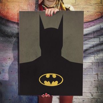 a woman holding up a batman poster in front of her face