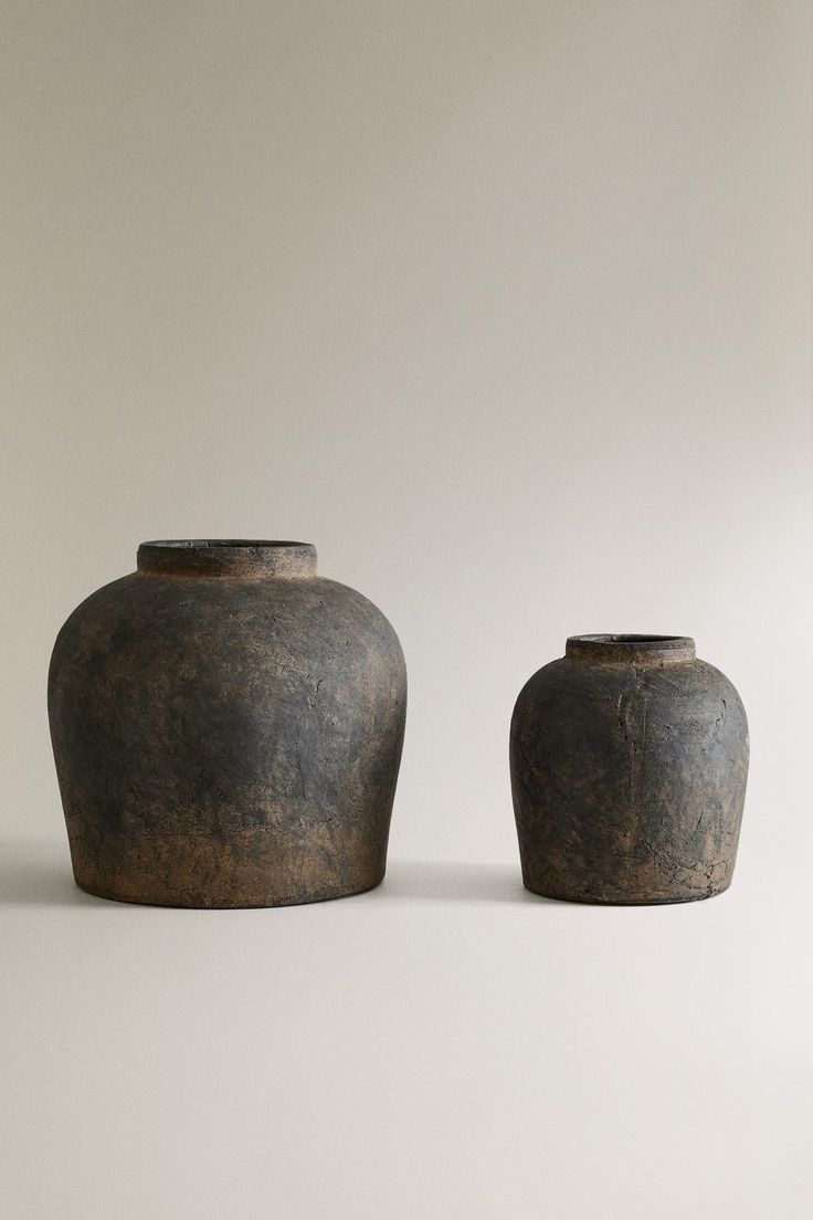 two brown vases sitting next to each other on a white surface with no one around them