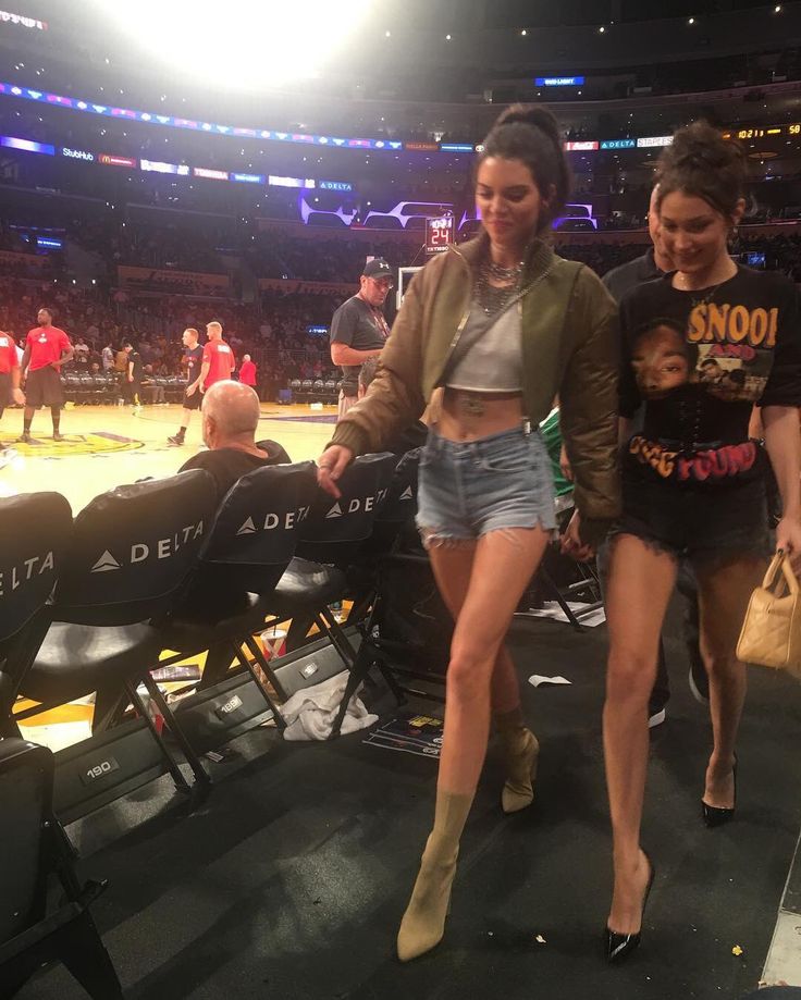 two women walking down the court at a basketball game, one is wearing short shorts