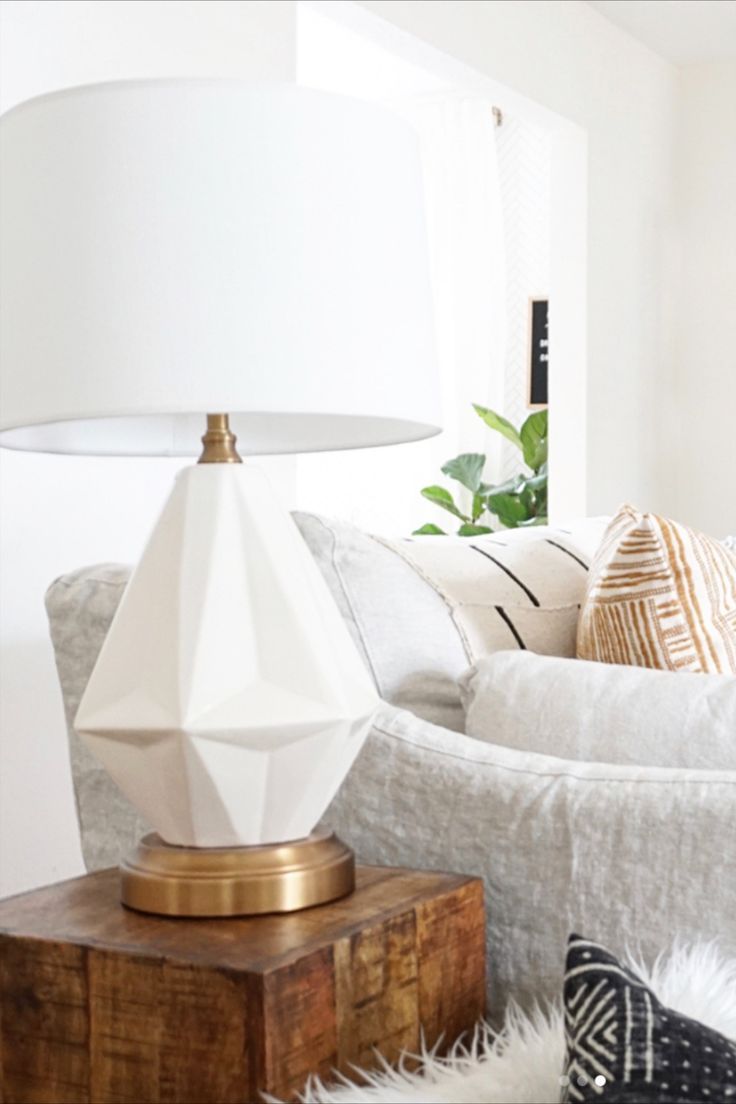 a white lamp sitting on top of a table next to a wooden box and pillows