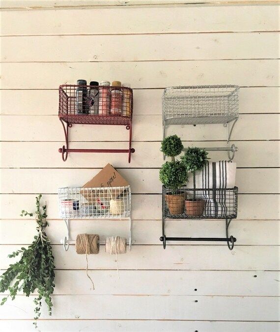 two metal shelves with plants on them against a white wooden wall next to a potted plant