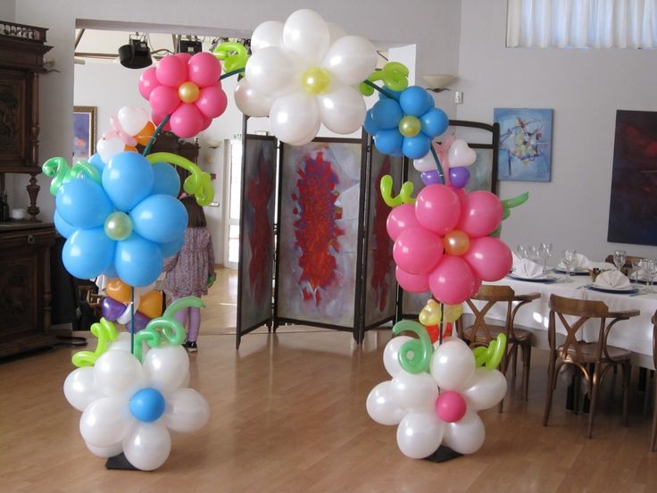 balloons in the shape of flowers are on display at a table with chairs and tables