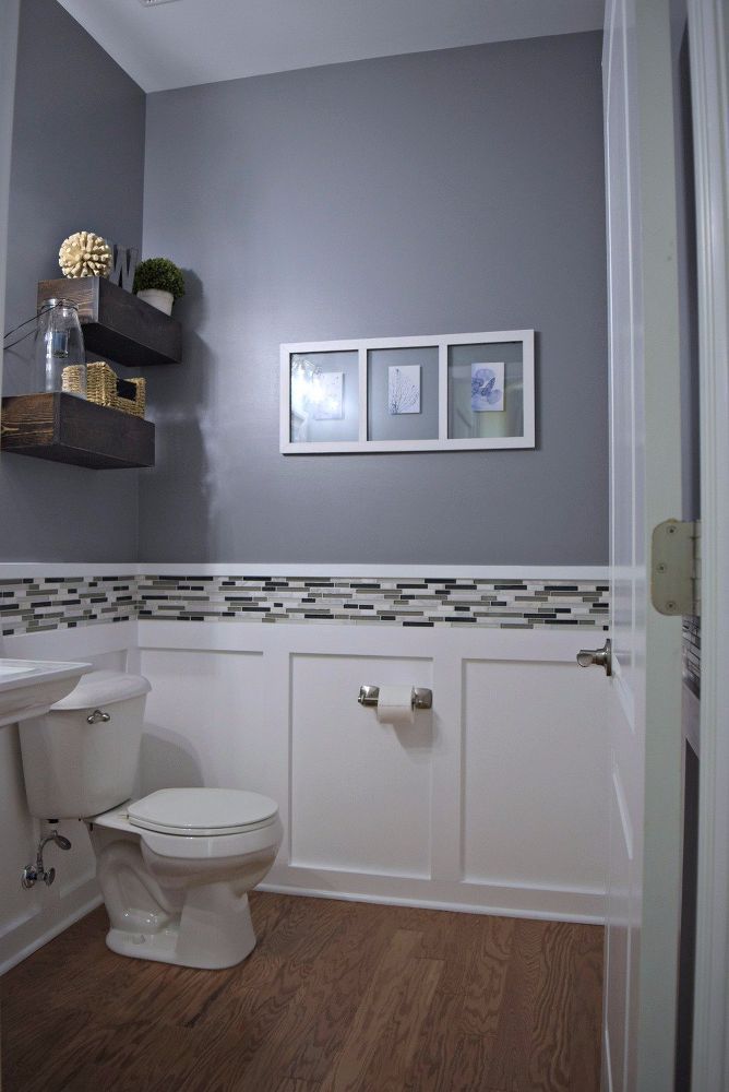 a white toilet sitting next to a sink in a bathroom under a framed picture on the wall