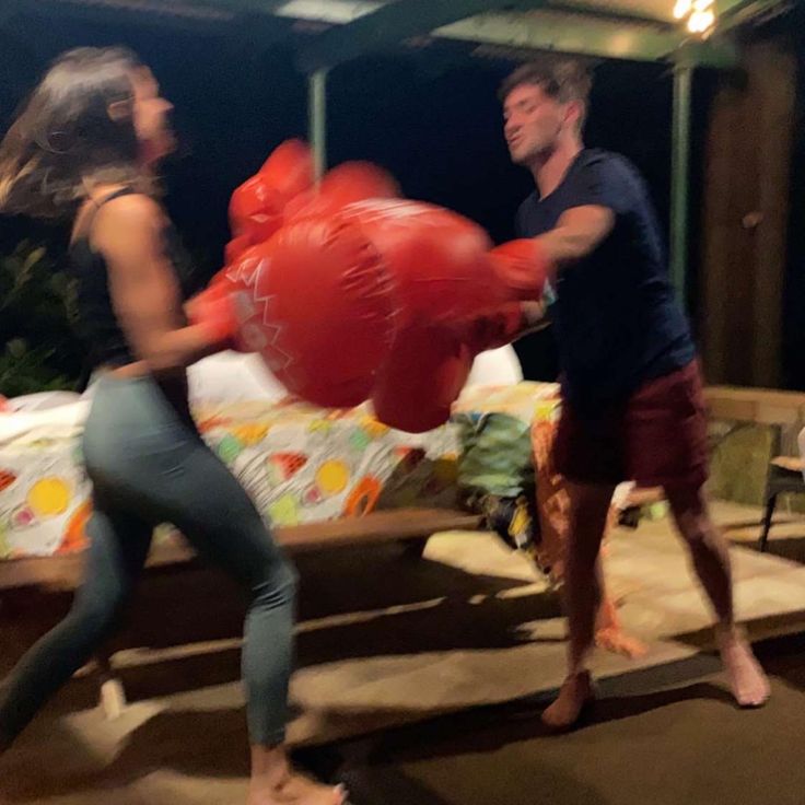 a man and woman standing next to each other in front of a red heart balloon