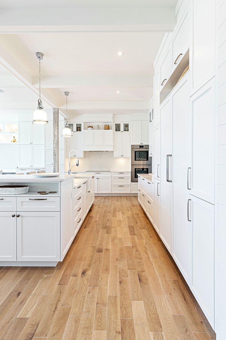 a kitchen with white cabinets and wood floors