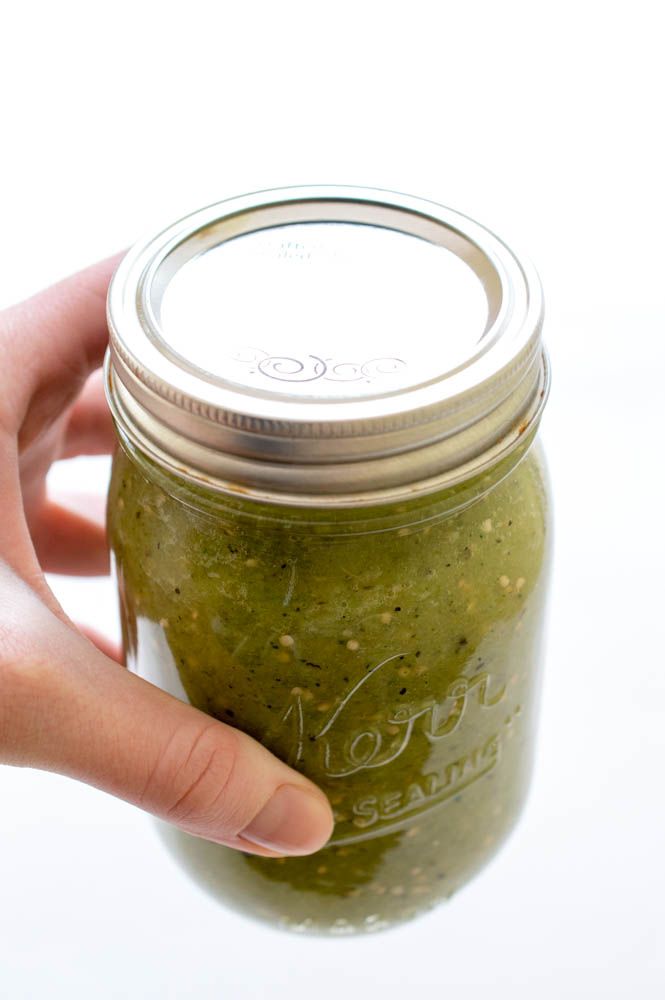 a hand holding a mason jar filled with salsa and the words super easy salsa verde