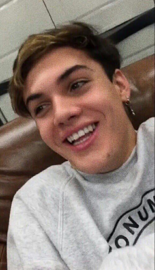 a young man smiling while sitting in a chair