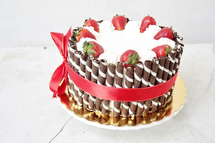 a chocolate cake with strawberries on top and ribbon around the edges, sitting on a plate