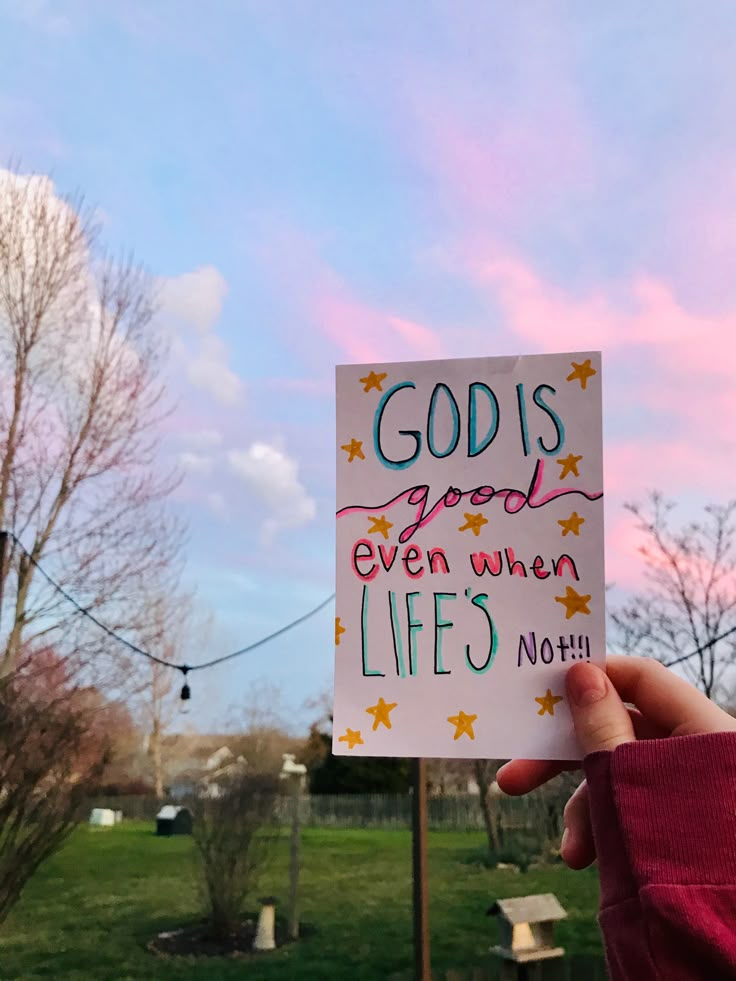 someone holding up a sign that says god is good even when life's not