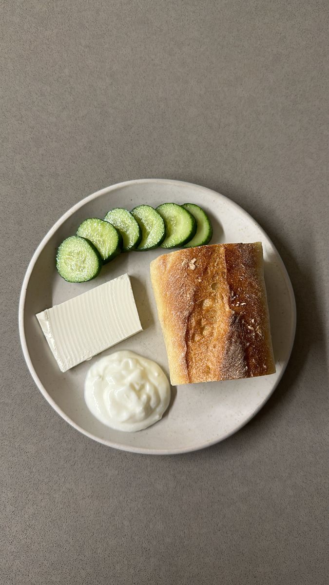 a white plate topped with cucumbers, cheese and crackers on top of a table