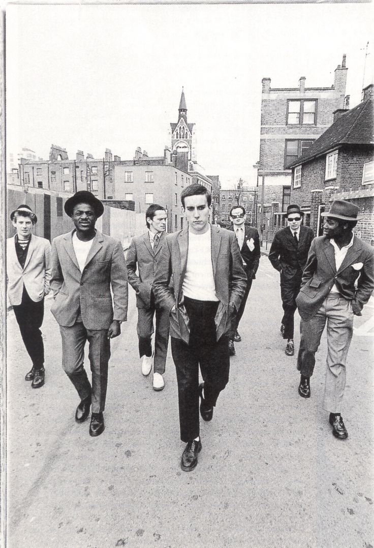 a group of men walking down a street next to each other in suits and ties