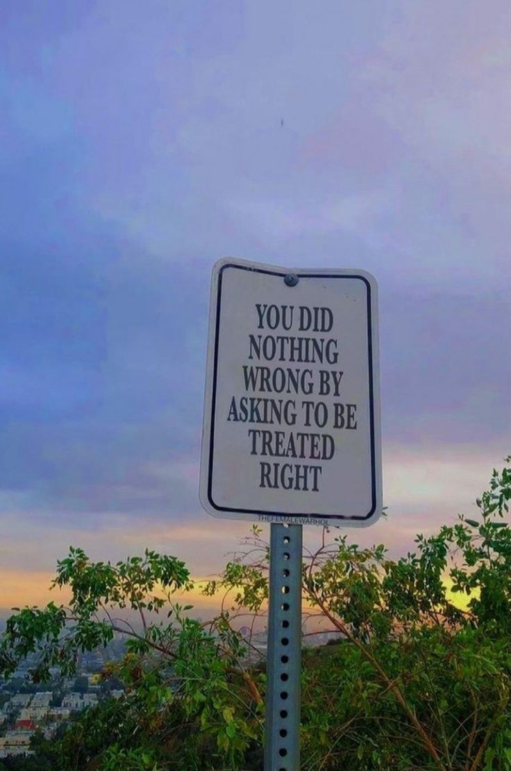 a sign that is on the side of a hill with trees in front of it