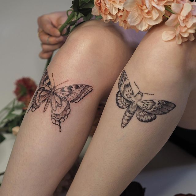 two butterflies tattoo on legs sitting next to each other with flowers in front of them