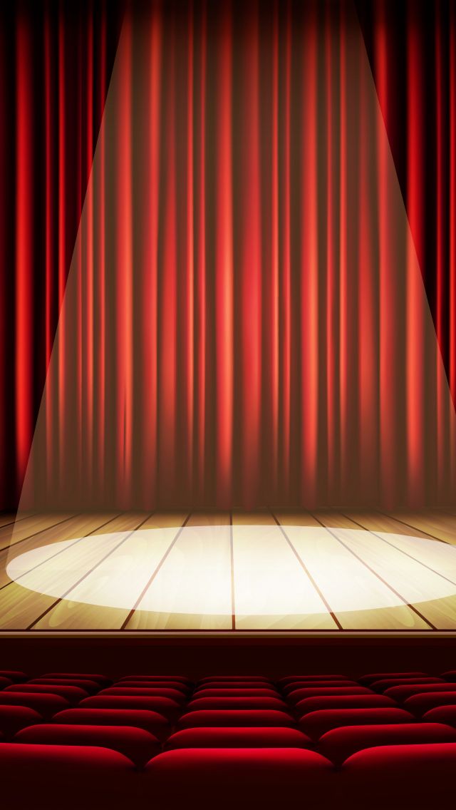 an empty stage with red curtains and seats