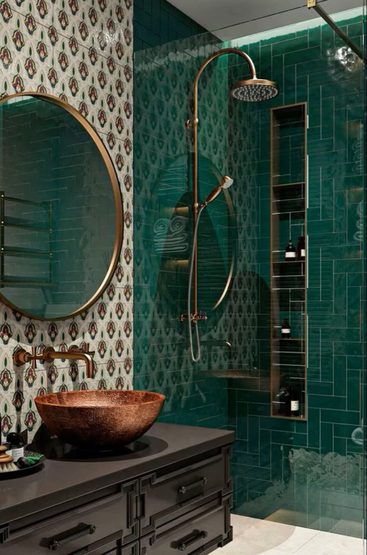 a bathroom with green tiled walls and a round mirror on the wall above the sink