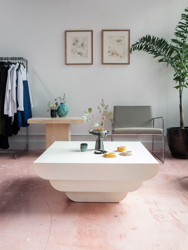 a white coffee table sitting in front of a potted plant on top of a hard wood floor