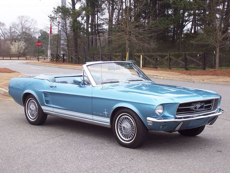 an old blue mustang convertible parked on the street