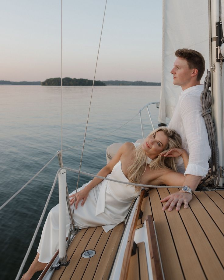 a man and woman sitting on the deck of a sailboat